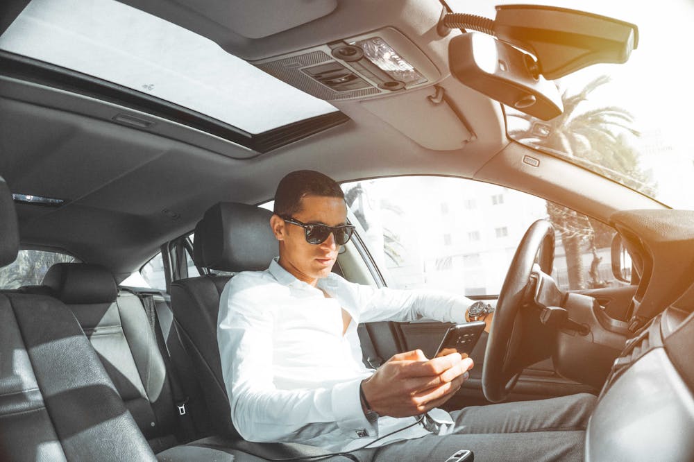 Man-In-Car-Looking-at-Smartphone