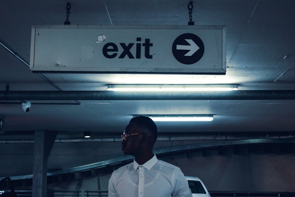 Man-standing-under-exit-sign