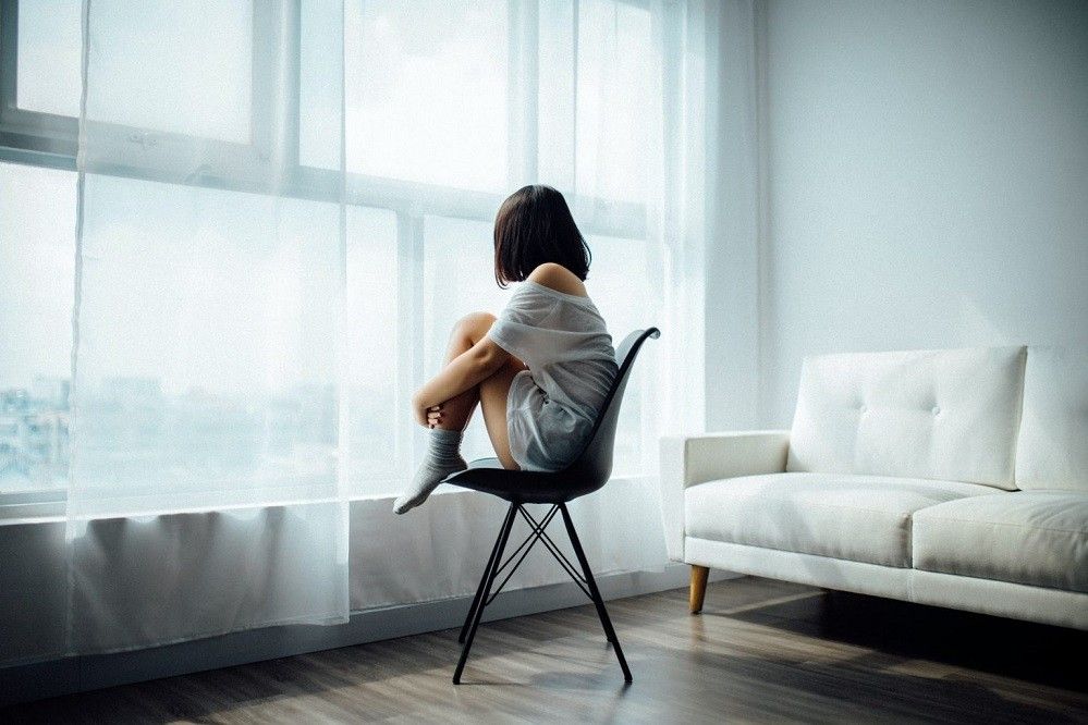 Woman-Sitting-On-Chair-By-Window