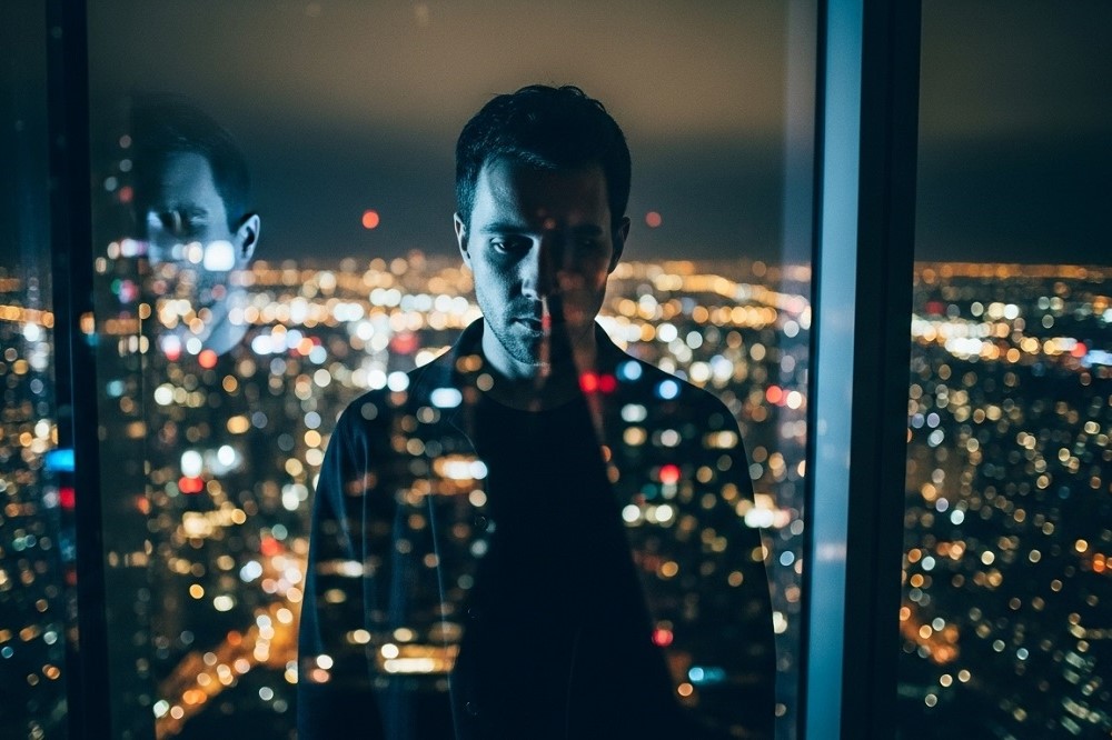 Man-standing-in-front-of-window-at-night