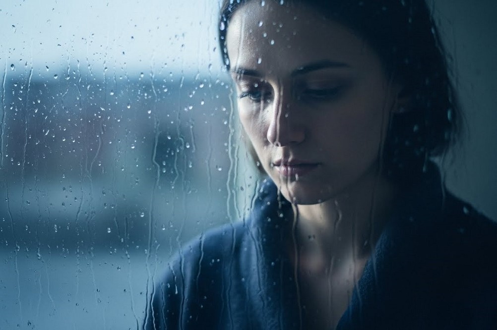 Solitary-Woman-Behind-Rain-Soaked-Window